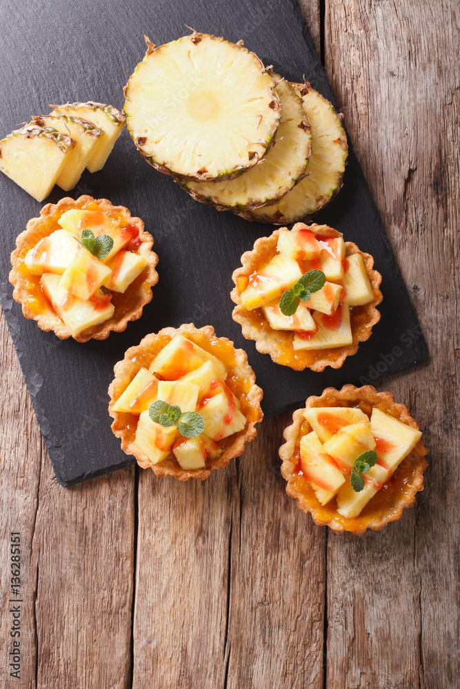 Delicious tartlets with fresh pineapple and jam closeup on the table. vertical top view