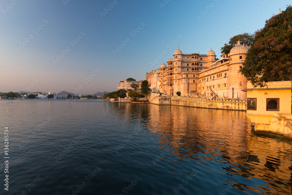 Udaipur cityscape at sunset. The majestic city palace on Lake Pichola, travel destination in Rajasthan, India Udaipur cityscape at sunset. The majestic city palace on Lake Pichola, travel destination in Rajasthan, India