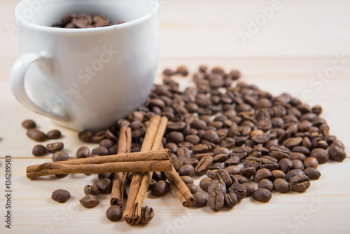 coffee beans in cup. Coffee cup and coffee beans on wooden background. coffee with cinnamon, coffee with additives. Coffee beans and cinnamon sticks 