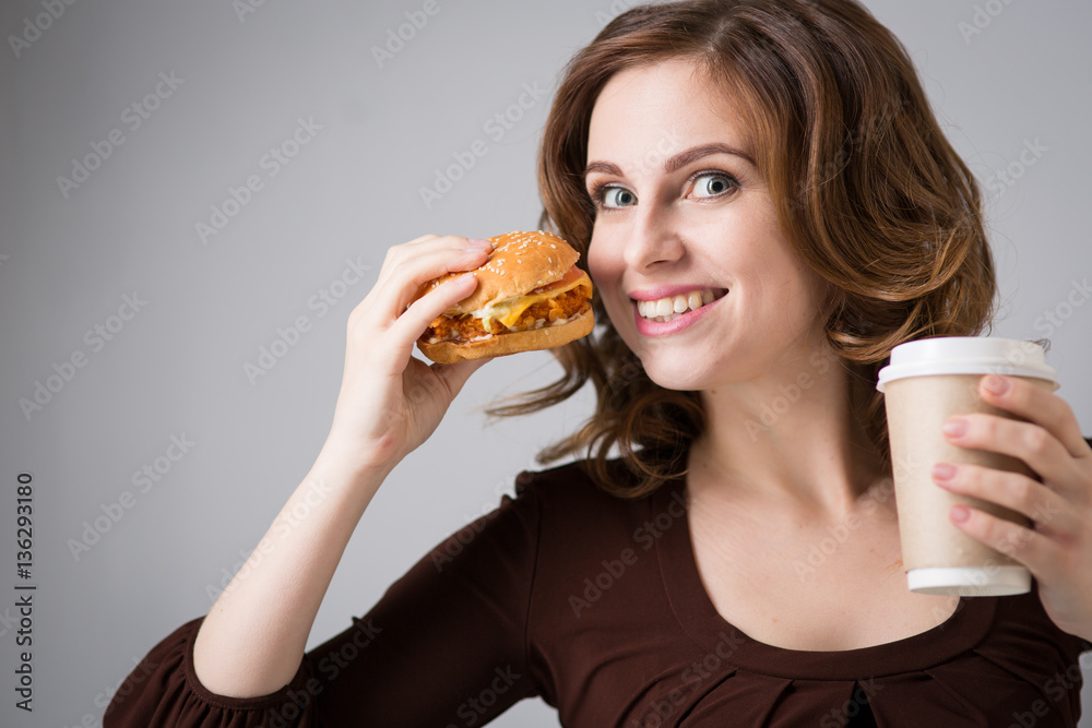 woman with a hamburger and a cup of coffee woman with a hamburger and a cup of coffee