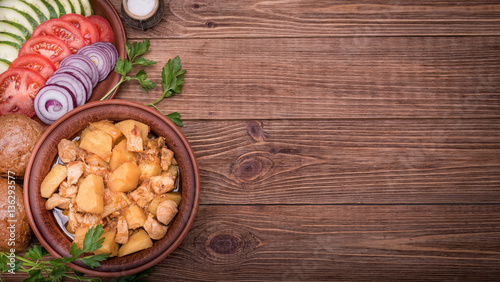 Meat stewed with potatoes in bowl on wooden background.