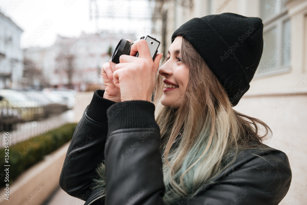 Cheerful woman wearing hat holding camera. Cheerful woman wearing hat holding camera.