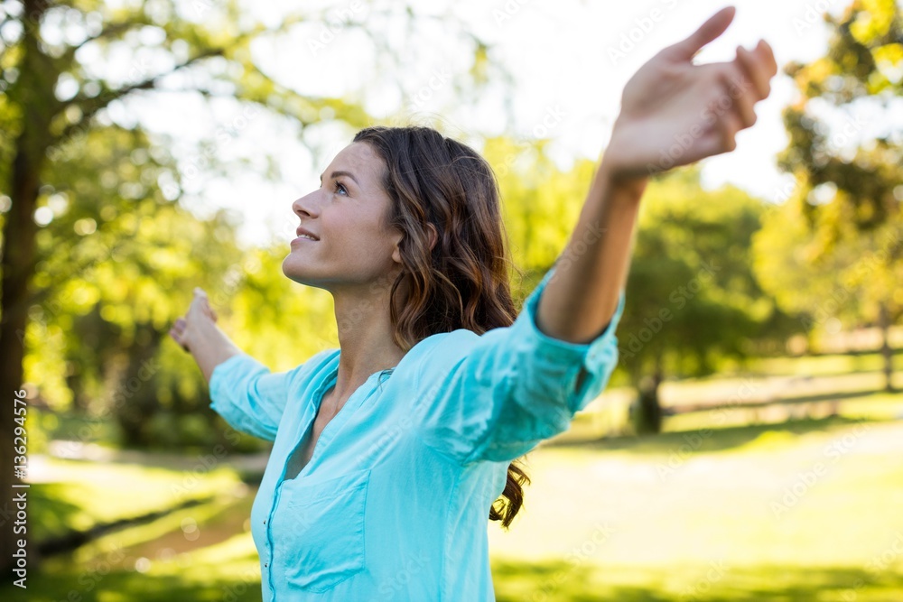 Woman standing with arms outstretched in park Woman standing with arms outstretched in park