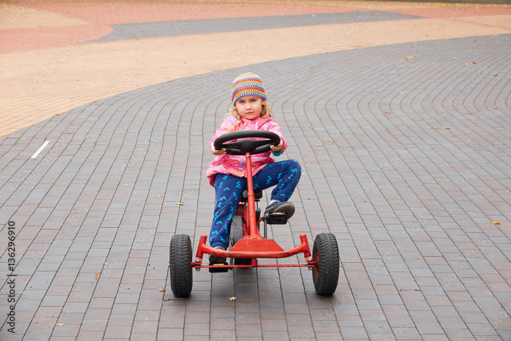 Little girl having fun driving a pedal car in day. Little girl having fun driving a pedal car in day.