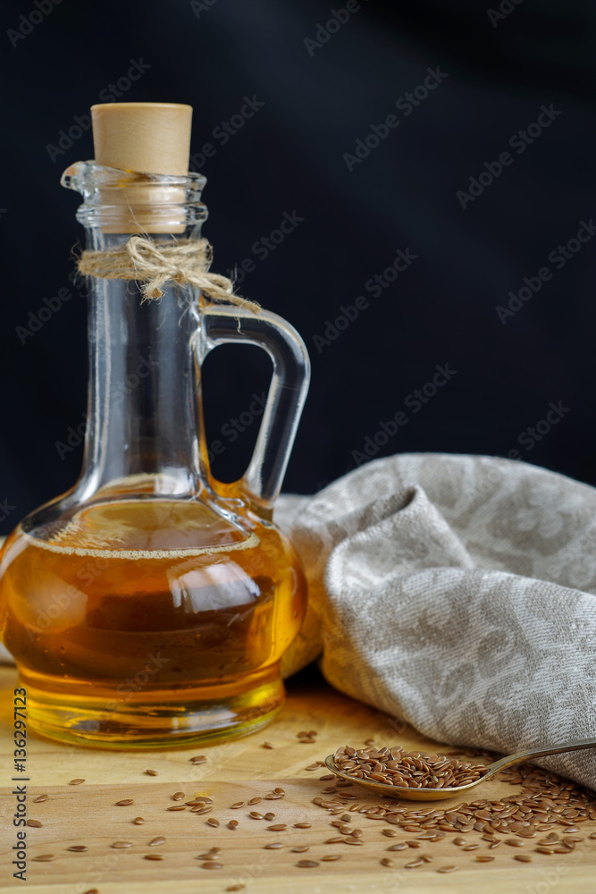Flax seeds on spoon and linseed oil in glass jug on wooden cutti