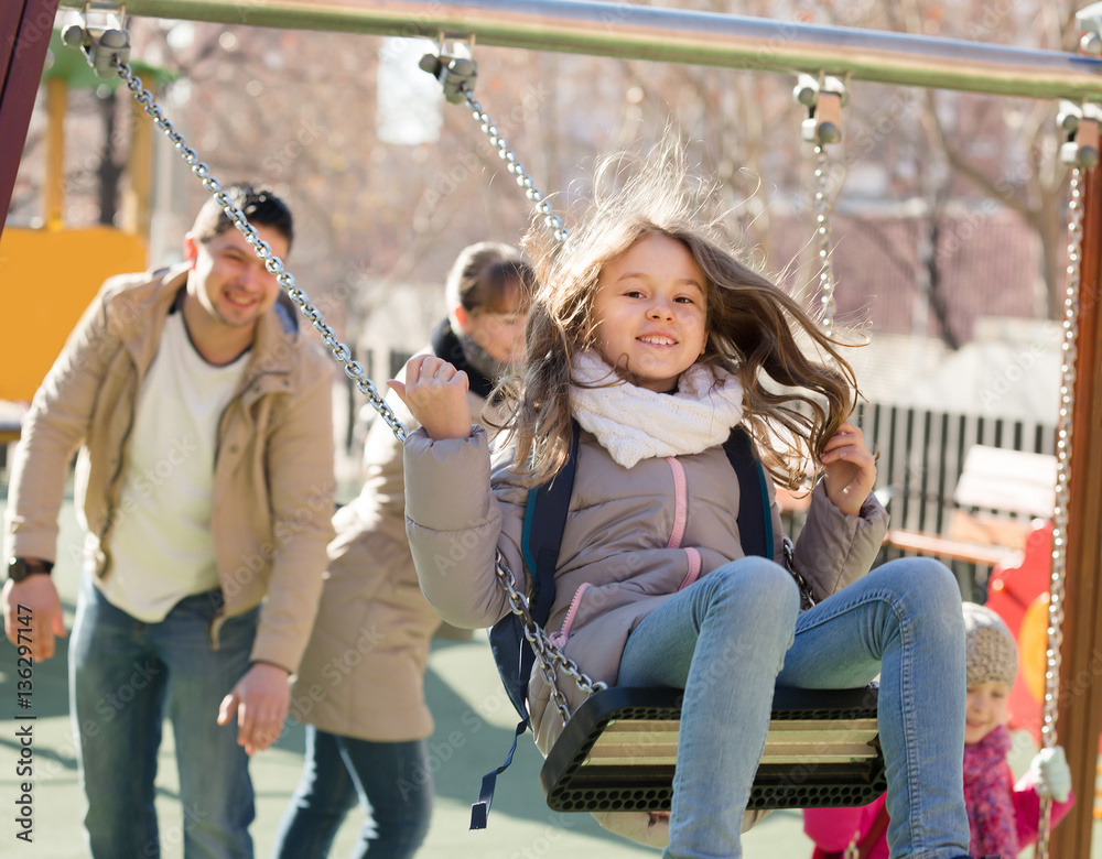 Obraz premium Cheerful family spending time at children swings