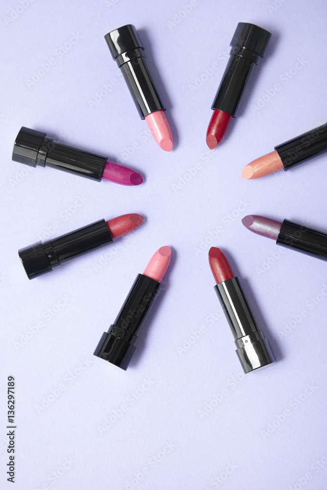 Lipstick make up arranged in a circle on a pastel purple background, with blank space below Lipstick make up arranged in a circle on a pastel purple background, with blank space below