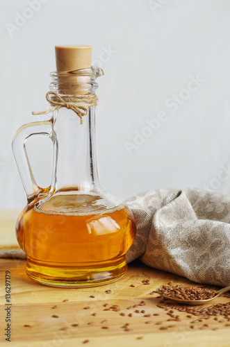Flax seeds on spoon and linseed oil in glass jug on wooden cutti photo