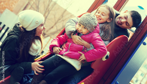 parents with two daughters playing at children's slide