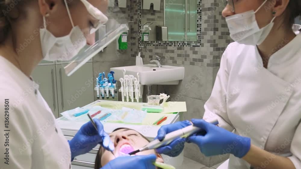 Dentists treat tooth girl. Teeth whitening. Dental Curing Light. Close-up.
Dentists treat tooth girl. Teeth whitening. Dental Curing Light. Close-up.