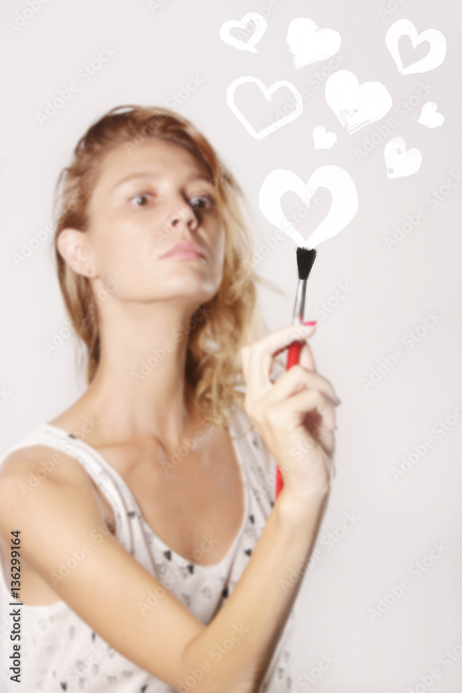 Young woman painting hearts on the transparent glass Young woman painting hearts on the transparent glass