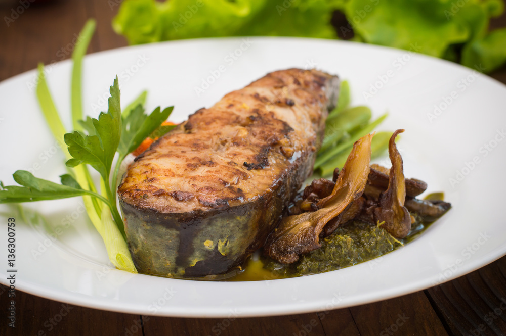 Tasty baked fish on plate on table close-up. Wooden background. Top view. Close-up Tasty baked fish on plate on table close-up. Wooden background. Top view. Close-up