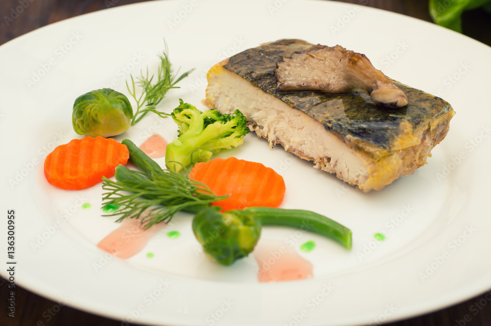 Tasty baked fish on plate on table close-up. Wooden background. Top view. Close-up Tasty baked fish on plate on table close-up. Wooden background. Top view. Close-up
