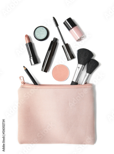 Aerial view of make up products spilling out of a pastel pink cosmetics bag, isolated on a white background