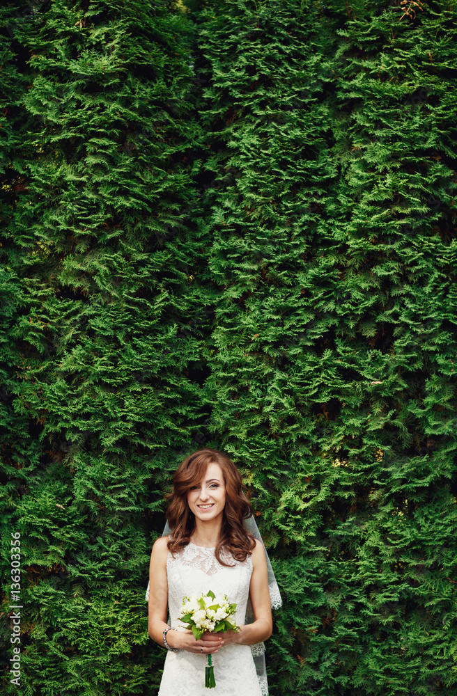 The charming bride stands near trees The charming bride stands near trees