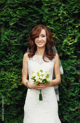 The charming bride stands near trees