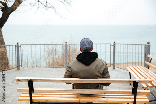 Back view picture of young african man on a bench