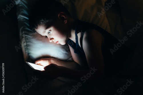 Obraz na płótnie 7 years old child boy using smartphone at night w salonie