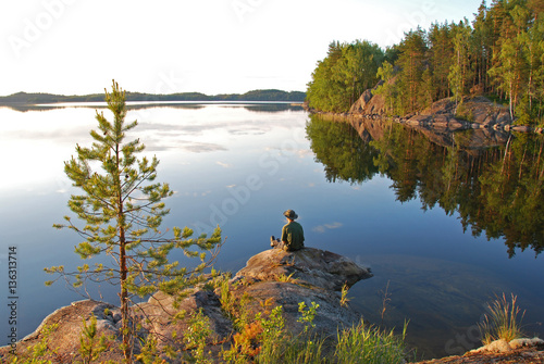 Canvastavla Man sitting at still Saimaa lake in Finland at sunset