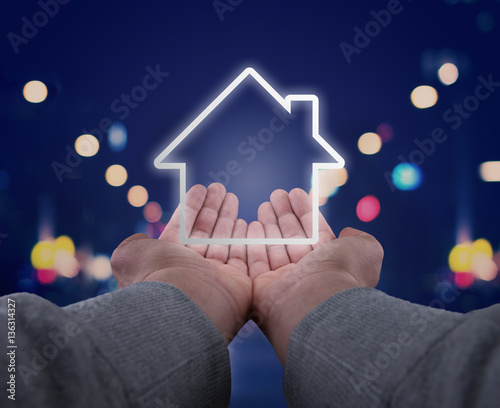 Photos two hands, seen firsthand supporting an abstract house