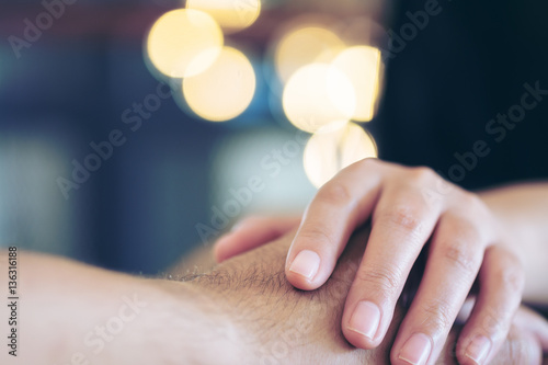 A man and a woman holding each other hands with feeling love and warmness with bokeh background