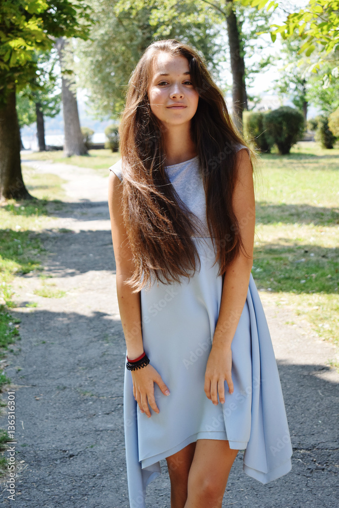 Naklejka premium Portrait of beautiful teenage girl in blue blouse, against green