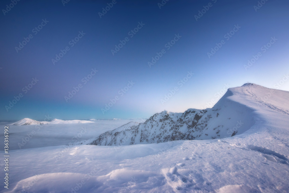 Obraz premium Mountain range above the clouds in the evening Twilight