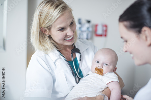 Female pediatrician holding baby at examination photo