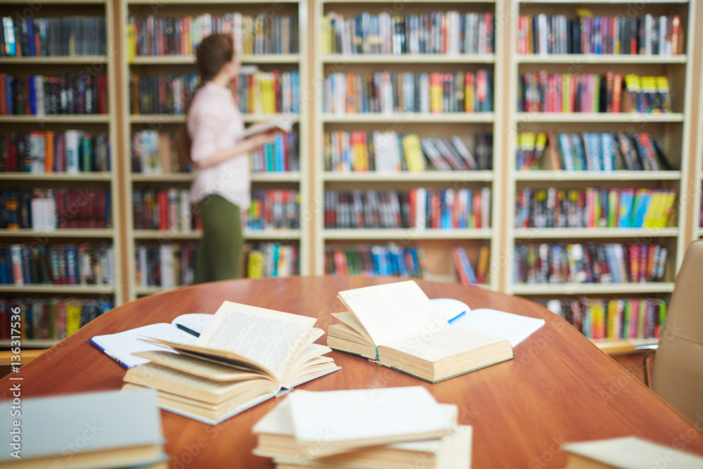 Open books on desk and human by bookshelf on background Open books on desk and human by bookshelf on background
