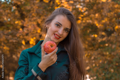 young beautiful girl with long hair holds an Apple in his hand and smiling close-up