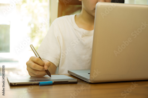 Teenage student working on laptop on wooden table