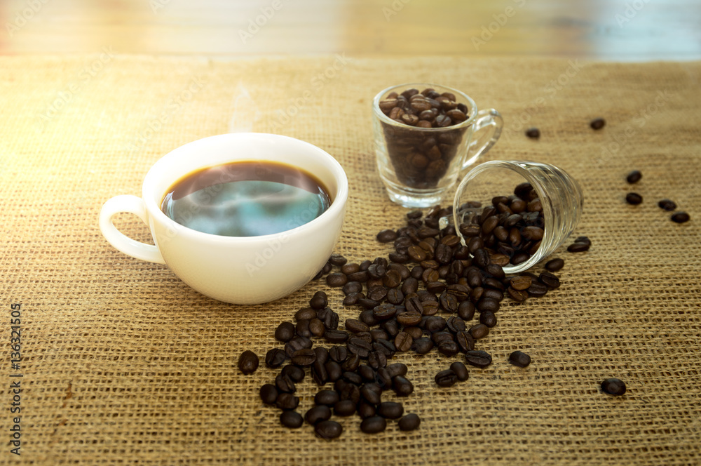Fototapeta premium Cup of black coffee and coffee beans on sackcloth