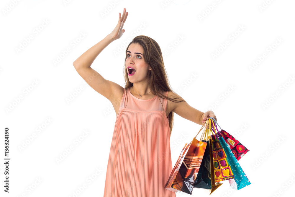 young girl in bright dress looks toward the raised arm up while the other hand holds lot of packages is isolated on white young girl in bright dress looks toward the raised arm up while the other hand holds lot of packages is isolated on white