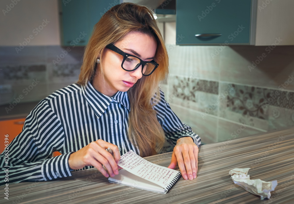 girl in glasses reads and looks at records in a paper notebook