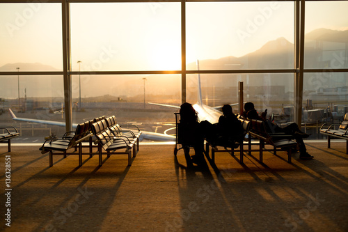 Passenger sitting in a lobby airport waiting for flight in silho photo