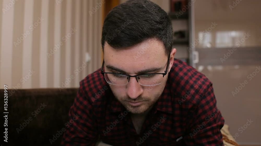 Young man lying on the couch and gaining a sms on a tablet Young man lying on the couch and gaining a sms on a tablet