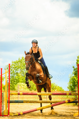 Jockey young girl doing horse jumping through hurdle © Voyagerix