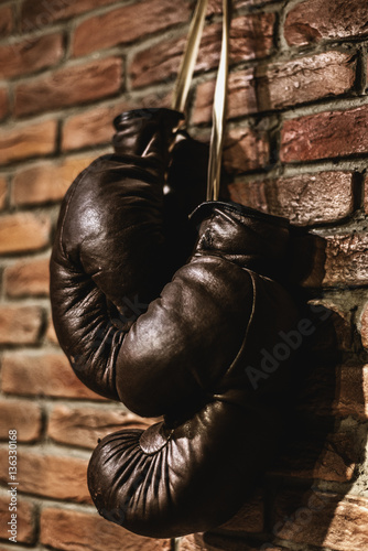 Pair of brown retro boxing gloves hanging on wall © romanets_v