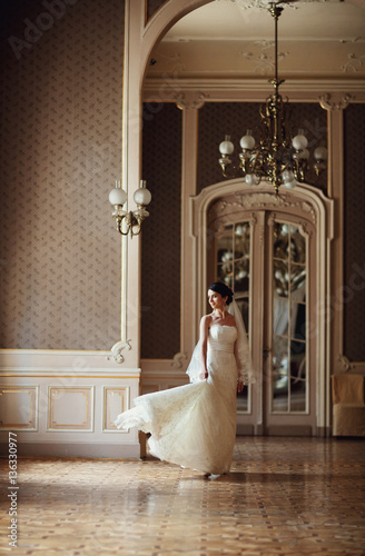 bride holding train of her dress in beautiful hall