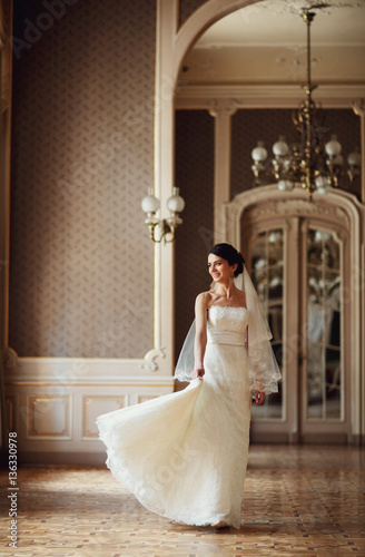 bride holding train of her dress in beautiful hall
