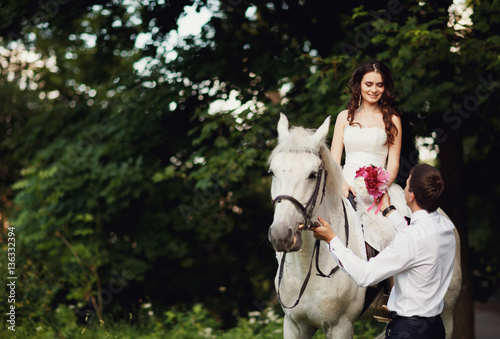 Bride o the luxury white horse recieving flowers from groom