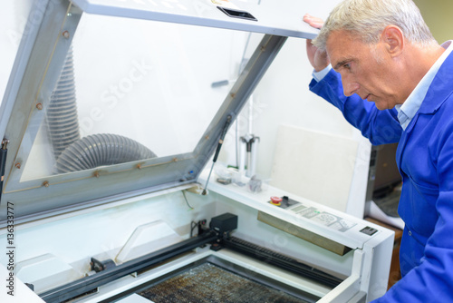 Mature man looking into printing machine