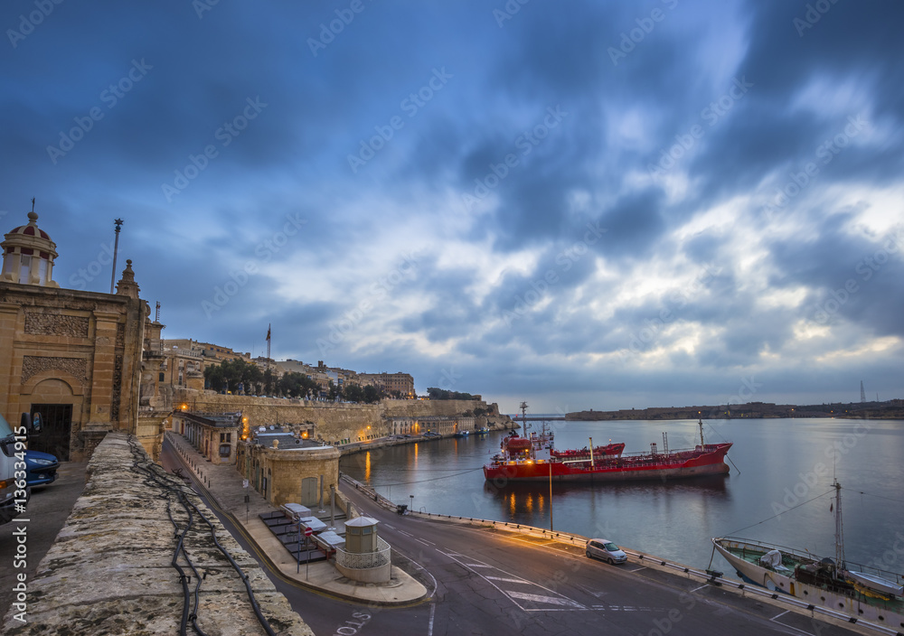 Fototapeta premium Valletta, Malta - Beautiful dawn and morning lights at the ancient walls of Valletta waterfront with ships and nice blue clouds