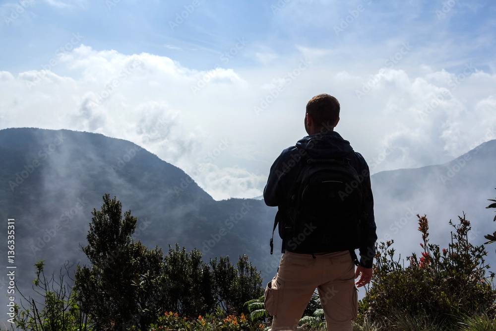 Naklejka premium Backpacker looking at misty mountains