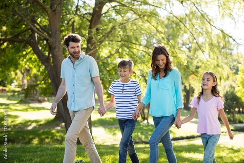 Happy family with hand in hand walking in park