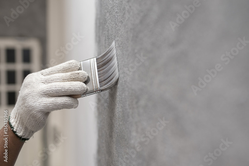 hand of worker use brush for color paint concrete Loft style on wall photo