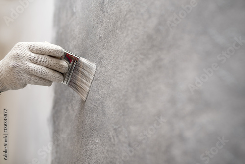 Fototapeta Naklejka Na Ścianę i Meble -  hand of worker use brush for color paint concrete Loft style on wall
