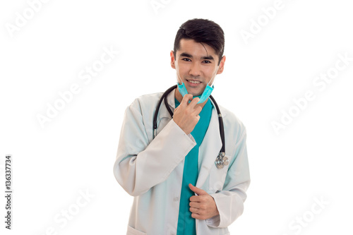 young male doctor with stethoscope in uniform and mask posing isolated on white background