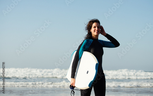 Photography Surfer woman leaving the sea after surfing with bodyboard