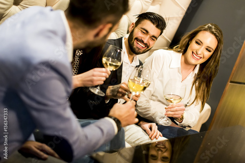 Group of young people celebrating and toasting with white wine